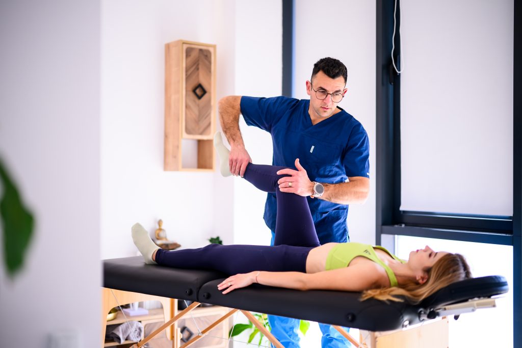 Radu Conea testează forța piciorului unei paciente, pe masa de terapie, la Fitway Kinetoterapie Cluj