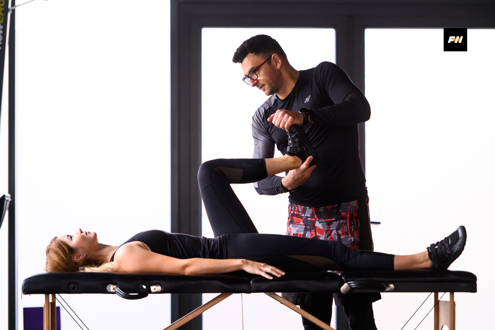 Radu Conea testează musculatura șoldului unei paciente întinse pe masa de terapie